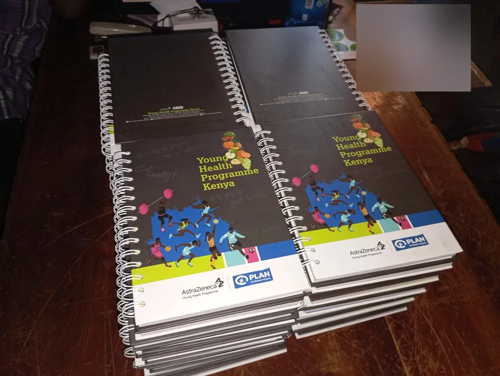 Two stacks of spiral-bound notebooks with printed hard covers for a youth health programme