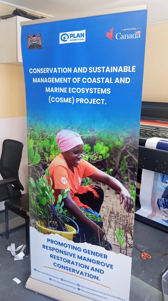 Roll-up banner for a coastal mangrove conservation project, standing in our print room beside the large-format printer